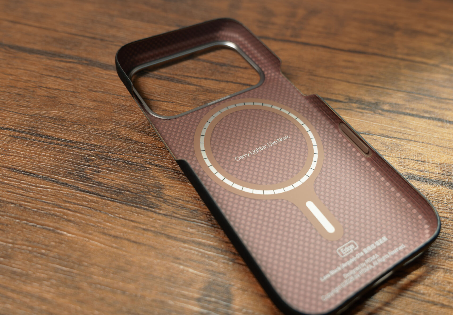 PITAKA Edge Caseを手に持ち、ダイヤ柄の背面と金属製カメラベゼルを見せている