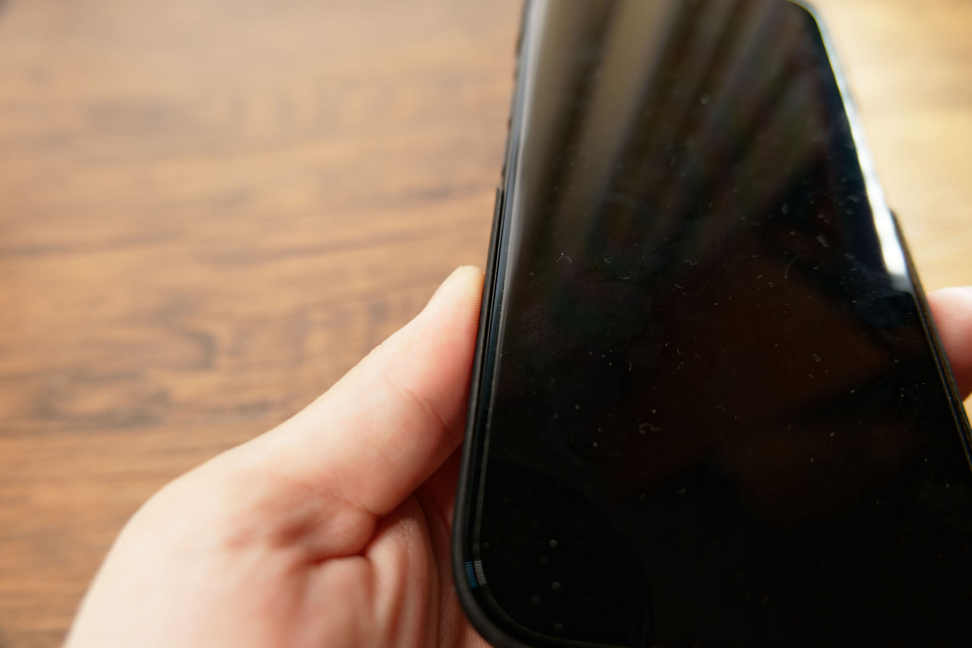 PITAKA Edge Caseを装着したiPhoneを手に持ち、画面側のフチの薄さを見せている